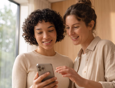 Two colleagues smiling as they choose a workout level in the BetterMe app on a smartphone in a sunlit office
