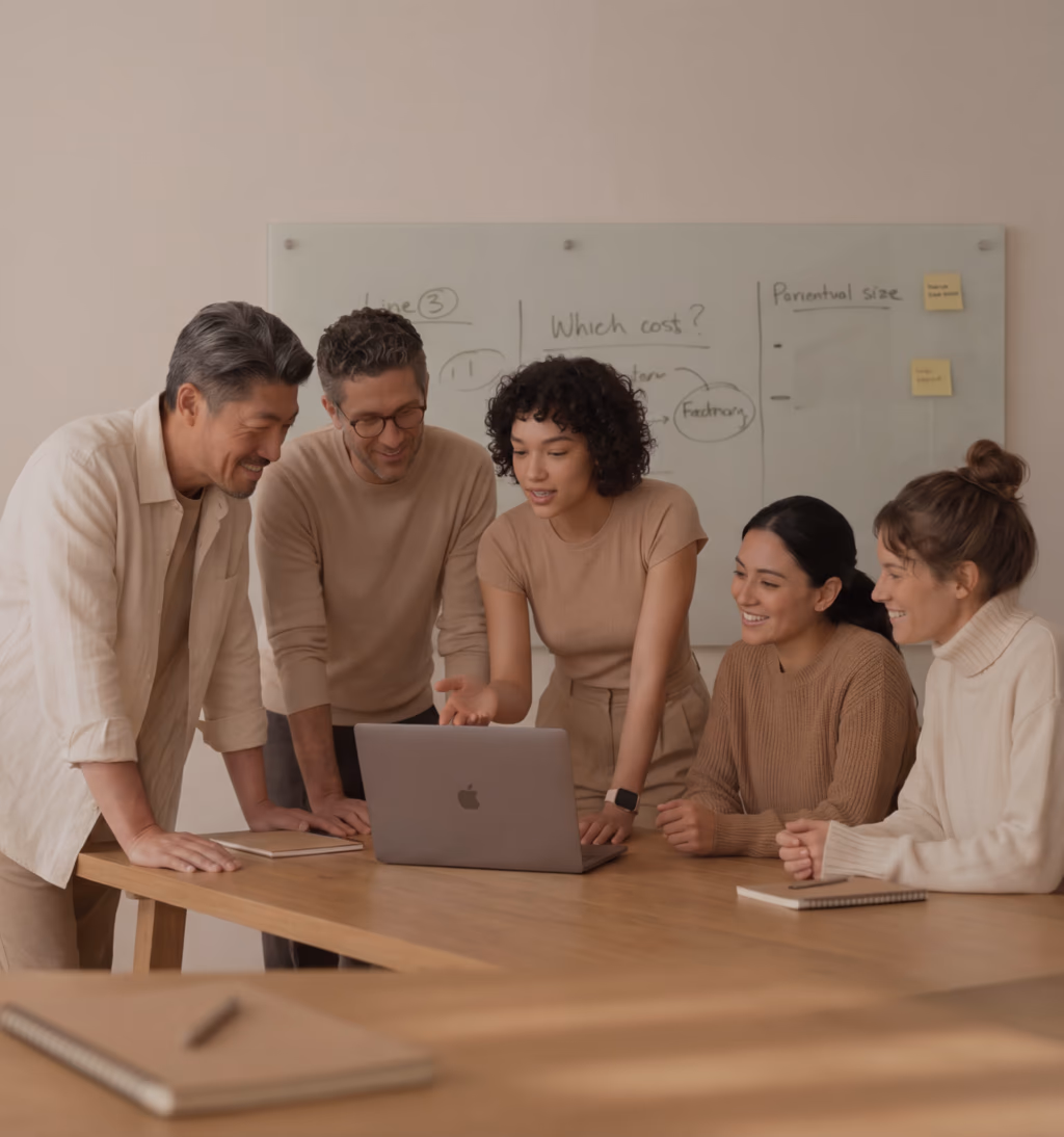 Team of colleagues gathered around a laptop in a meeting room checking their wellness challenge leaderboard