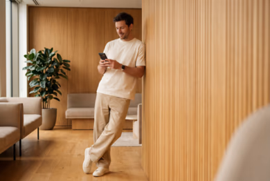 Employee checking the BetterMe Business app on a smartphone in a workplace lounge