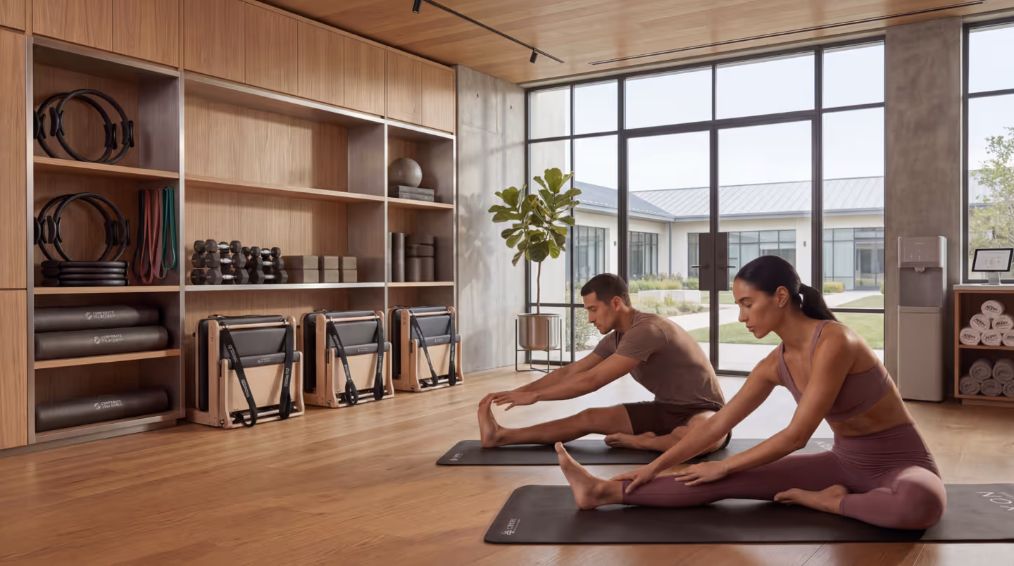 Two colleagues stretching side by side on yoga mats in a bright studio during a corporate wellness session