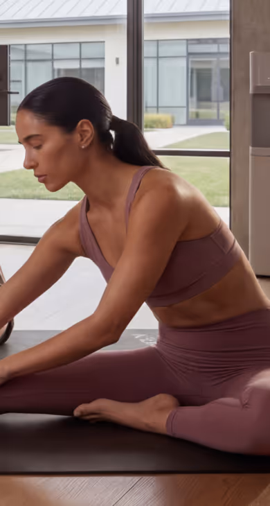 Two colleagues stretching side by side on yoga mats in a bright studio during a corporate wellness session